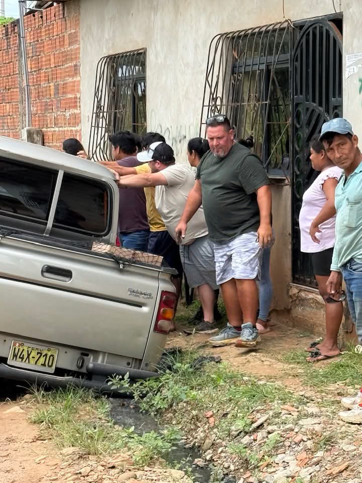 Community helping to push truck up from the side while dump truck pulls.